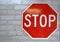 A bright red and white stop sign bolted to white brick wall