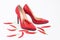 Bright red women`s stiletto heels. There are chili peppers nearby. Nice combination of shoes and pepper. Red color