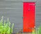 Bright red wooden door with iron door knocker and nail decoration in wall of colonial building