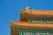 Bright roof of traditional Chinese building against blue sky - orange tiles and ornate painted walls