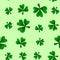 Bright seamless pattern of shamrock clovers on a green background.