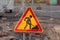 Bright shabby road warning sign informing about roadworks ahead