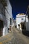 Bright shining isoalated empty narrow alley with cobblestones against deep blue sky and typical spanish white houses - Arcos de la
