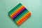 Bright silicone striped toy big Pop It closeup on blue background. Popit for kids playing with rainbow, pressing the