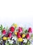 Bright spring flower arrangement. Lilac lupines, crimson tulips, white daffodils, and yellow flowers of trolius europaeus on a whi