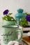 Bright still life with tea, cotton bolls, a book, a spoon and flowers with a lantern on the background. On the mug there