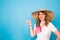 Bright studio portrait of attractive young woman pointing copyspace on blue background.