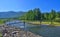 Bright summer landscape with light bridge over fast mountain riv