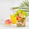 Bright summer lunch set with seafood salad with shrimps, red bell pepper, lettuce, croutons in plastic pack, fresh orange juice.