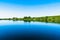 Bright summer nature panorama, forest trees and river with reflection in water, vivid tranquil and relax background