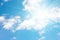 Bright sun on a blue sky with white clouds. Sunny sky as a background. Peaceful sky