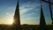 Bright sun hiding behind silhouettes of high church spire against blue sunset sky