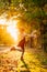 In bright sunlight, girl dancing with hat and plaything is in autumn Park