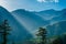 Bright sunlight shining through hole of clouds to dark scene of mountain village - India