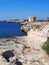 Bright sunlit view of the cliffs and coast in ciutadella menorca with deep blue sea and rocky cliffs with the historic castle an