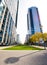 Bright sunny city street alley with tall buildings and grass patches in park