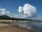 Bright sunny day. Calm river, sandy beach. Blue sky, big cloud