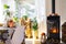 Bright sunny interior of the house with Black Metal Steel fireplace stove with fire and firewood with halloween decor and autumn