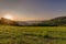 Bright sunrise rural panoramic landscape with a wide view over fields, forest, hills and misty valleys towards the