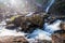 Bright sunrise shining on the waterfall, gently water falling from the cliff on the stream, abstract bokeh backgrounds, Khlong Lan