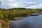 Bright sunset with reflection in water clouds a small river Kempendyay in Yakutia off a cliff and spruce forests in the wild North