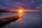 a bright sunset with the sun in a narrow skylight with sunbeams and a dramatic cloudy sky over a frozen lake with an old wooden