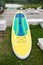 A bright surfboard lies on the green grass after or before training
