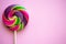 Bright swirl lollipop on pink background with copy space