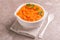 Bright tasty pureed carrot soup in clay bowl with napkin