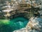 A bright turquoise clear reservoir surrounded by relief canyons overgrown with moss