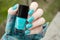 Bright turquoise Nail art manicure. Holiday style nails with neon glitter. Woman holds Bottle of Nail Polish