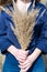 Bright vertical photo of bouquet made of dried autumn bushgrass in young woman hands.