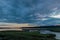 Bright vibrant cloudy sunset over a thick dark green wetland full of tall grass and streams of water