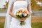 Bright wedding bouquet of roses, Queens, decorative cabbage and green leaves in the hands of the bride