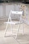 Bright white comfortable simple wooden folding chair out of focus interior kitchen background.