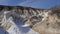 Bright white snow covers ground around interesting geologic site.