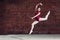 In bright white studio. Young dancer performing a jump in the air