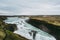 Bright white waters of Gullfoss in Iceland. Groups of tourists admiring the view