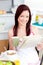 Bright woman eating cereals and reading newspaper