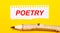 On a bright yellow background, a large wooden pencil and a sheet of torn paper with the text POETRY