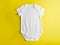 On a bright yellow background, a model of a children`s cotton bodysuit for boys and girls. Flat layout for the design and