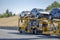 Bright yellow big rig car hauler semi truck transporting cars on the two level modular semi trailer running on the highway road