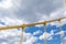 Bright yellow cables and joints of a self anchored suspension bridge against a blue sky with heavy clouds, creative copy space