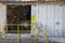 Bright yellow caution signs at the open entrance to an old machine shed