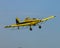 Bright yellow crop duster airplane soaring across a pristine blue sky