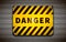 Bright yellow danger sign on metallic grid, industrial background