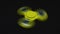 Bright yellow fidget finger spinner on dark background.