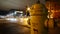 Bright yellow fire hydrant stands on a rainy urban street at night