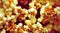 Bright yellow grains of crispy caramel popcorn scattered across wooden table.