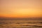 A bright yellow gray pink sunset sky over the ocean